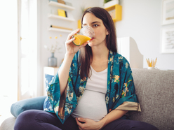 Mujer embarazada bebiendo jugo de naranja.