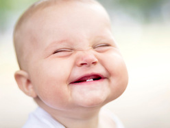 Grinning baby with two lower teeth showing