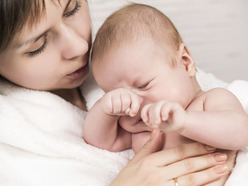 Worried mum looking at her baby as he rubs his eyes