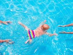 Baby mit Schwimmwindel von oben im Schwimmbecken