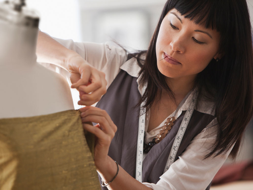 woman seamstress putting pins in clothing