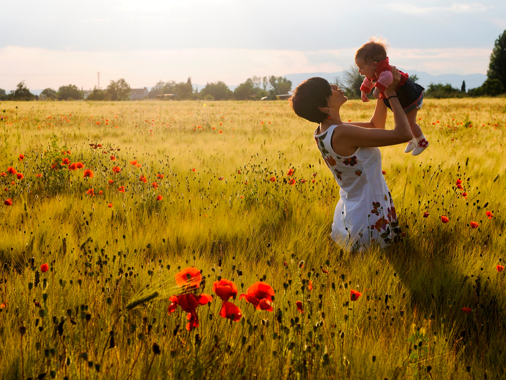 A mother holding a baby in a field