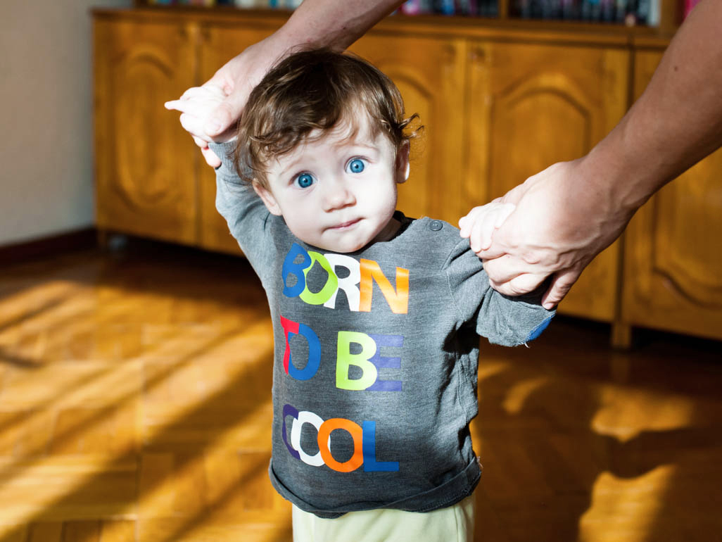 A father helping a toddler walk