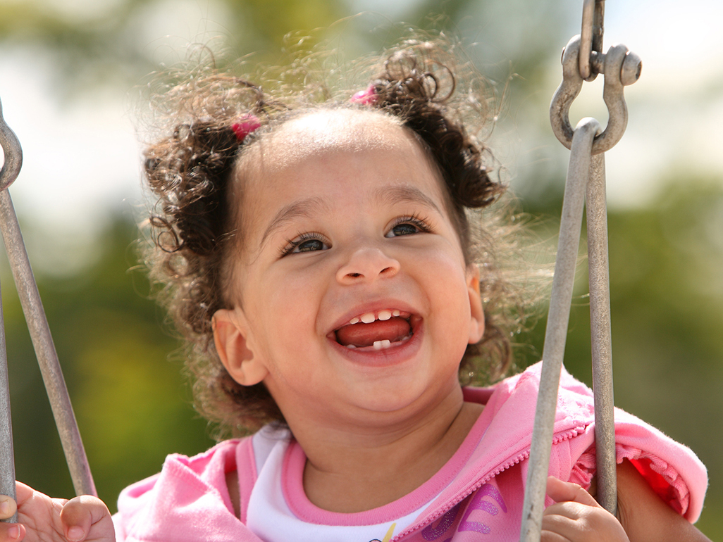 A baby laughing while swinging in a swing