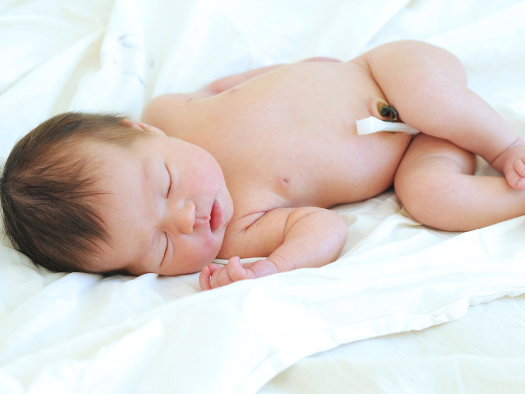 newborn sleeping on the side with umbilical cord stump