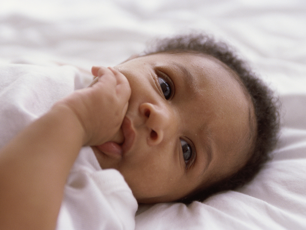 Baby on the bed suckling thumb