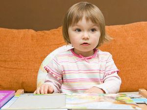 small girl sitting in front of a table with books and papers on it