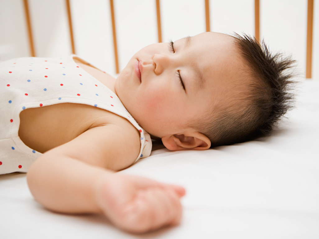 A toddler sleeping in a crib