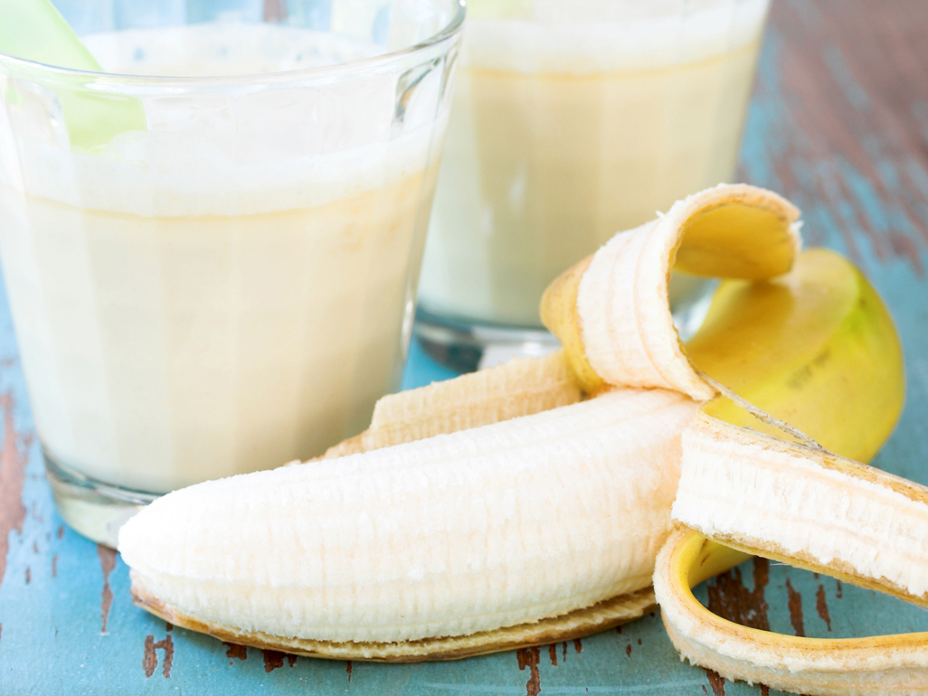 close up of a glass of milk and peeled banana