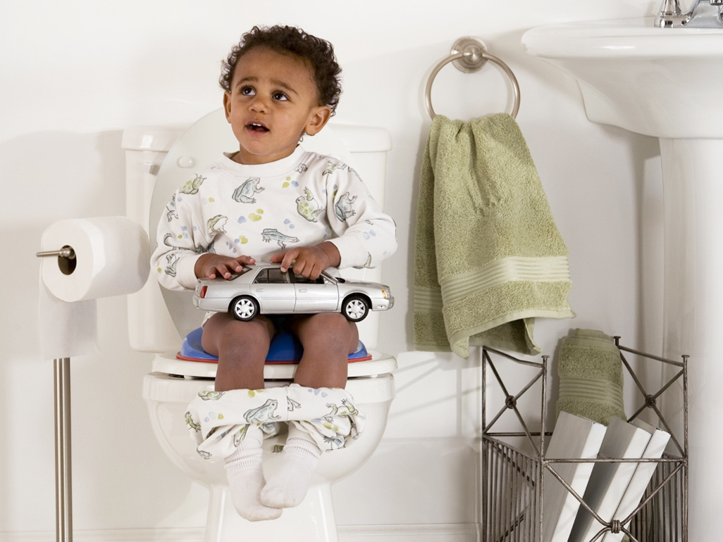 A toddler boy sitting on the toilet, potty training.