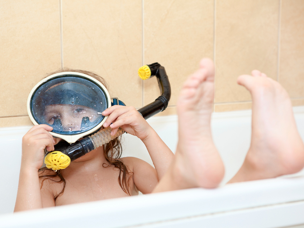 boy playing in his bathtub with feet up