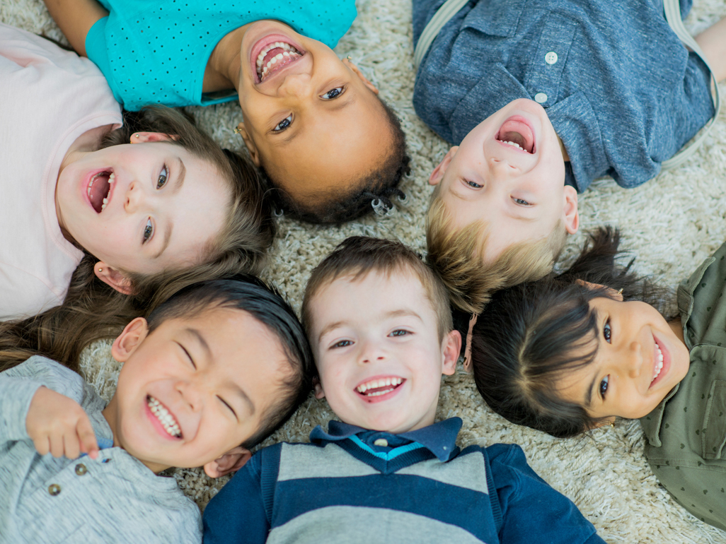 several preschool aged children laying on their backs looking up smiling