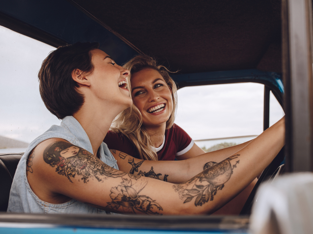 two women driving in car and smiling