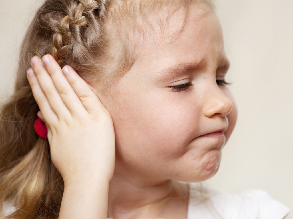 little girl holding her ear in pain