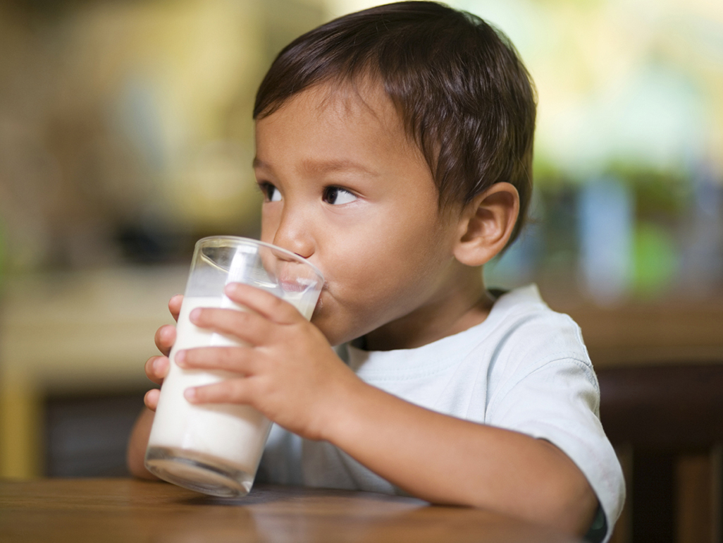 little boy drinking from a cup of milk