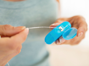 woman pulling dental floss from container