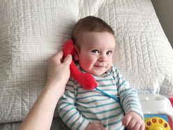 Baby talking on play telephone