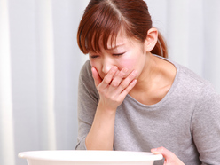 Pregnant woman sitting with a bowl, looking nauseous