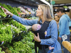 Babywearing mum doing the grocery shopping with her baby in a carrier.