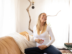 Woman smiling and holding her bump. 