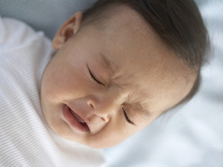 Baby in a white top sneezing 