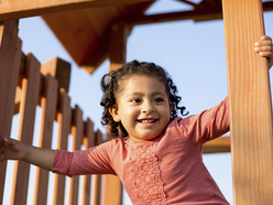 Happy preschooler holding on to a wooden railing