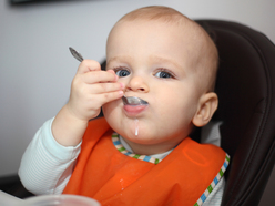 A baby feeding themself with a spoon 