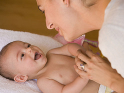 bebé en pañales sonriendo y jugando con su mamá