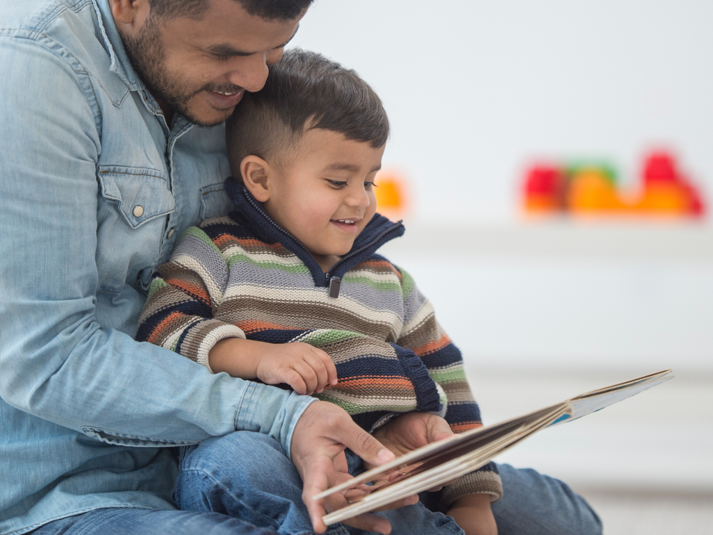 father reading a book to his son