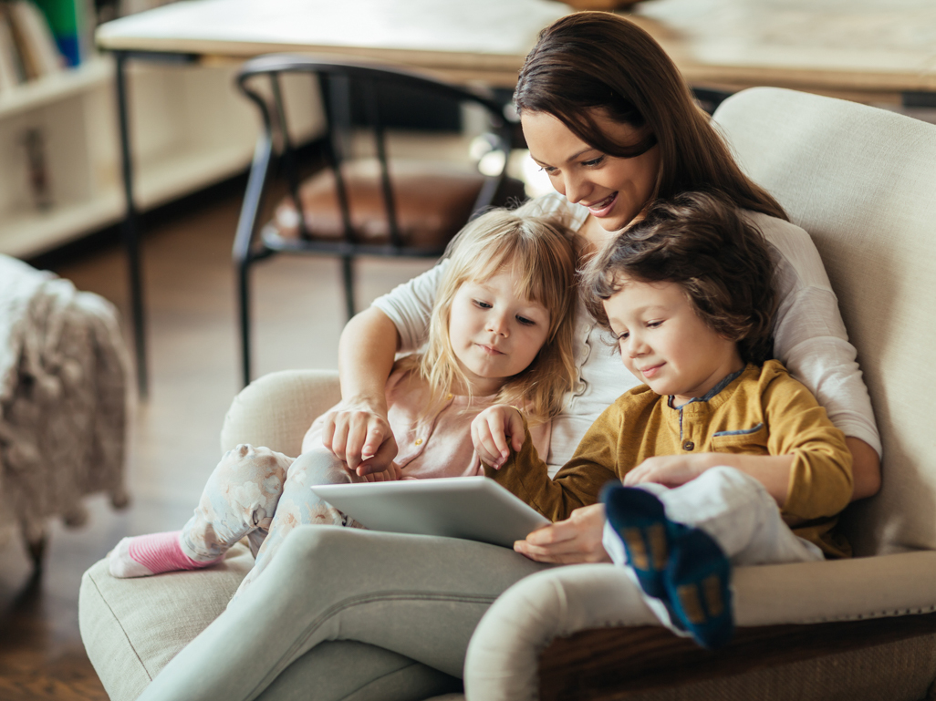 two small children sitting in moms lap looking at tablet