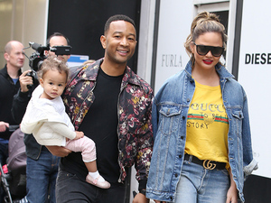 john legend and chrissy teigen walking outdoors with baby