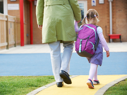 Mum holding child's hand at school gates