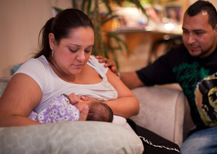 Mamá, papá y bebé mientras madre da el pecho