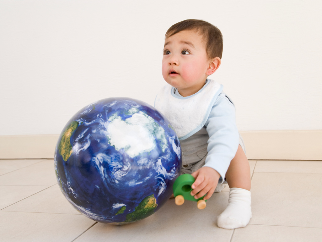 baby sitting next to a globe