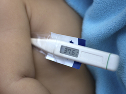 Fieberthermometer unter dem Arm eines Babys zeigt 37,2