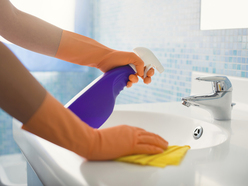 Gloved hands cleaning a bathroom sink 