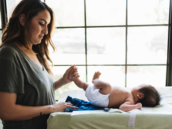 Young mother changing her baby's diaper