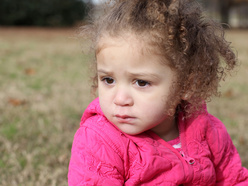 curly, sad looking girl in a jacket