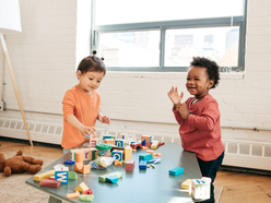 Two children playing with building blocks on table at daycare