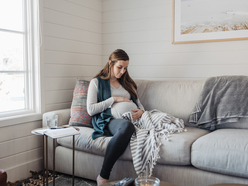 Pregnant woman sitting down and holding her bump