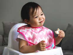 Toddler girl eating at highchair