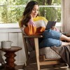 A woman lounges in a chair, with her feet tucked to the side, reading a new Amazon Kindle Paperwhite. 