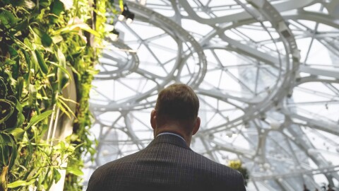 An image of the back of a man in a suit walking inside The Seattle Spheres at Amazon’s headquarters.