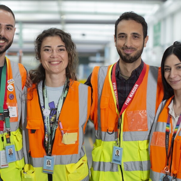 Team safety DLO1: four young men and women in orange vests are smiling at the camera