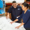 A photo of two Compac Industries employees observing material in a factory.