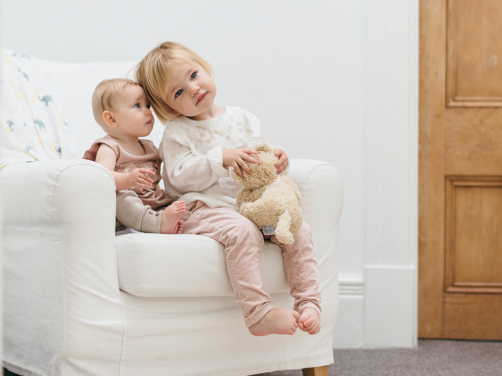 baby and a little girl sitting on a chair