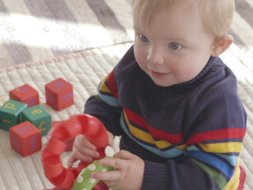 toddler in sweater playing with blocks