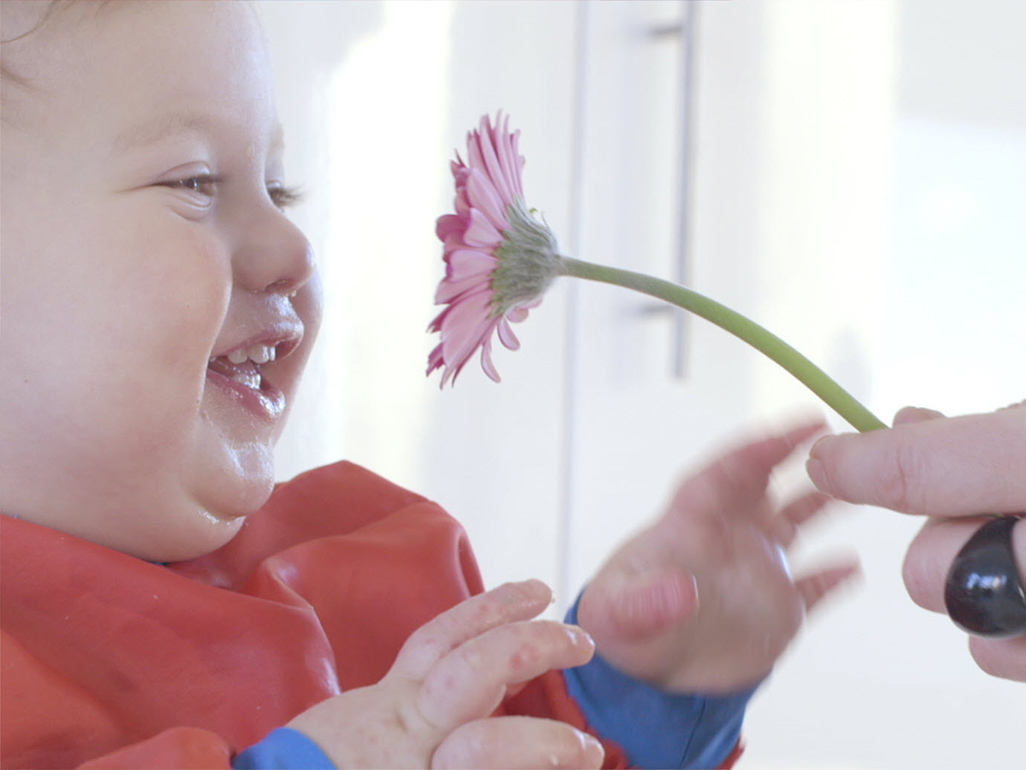 baby smiling at a flower