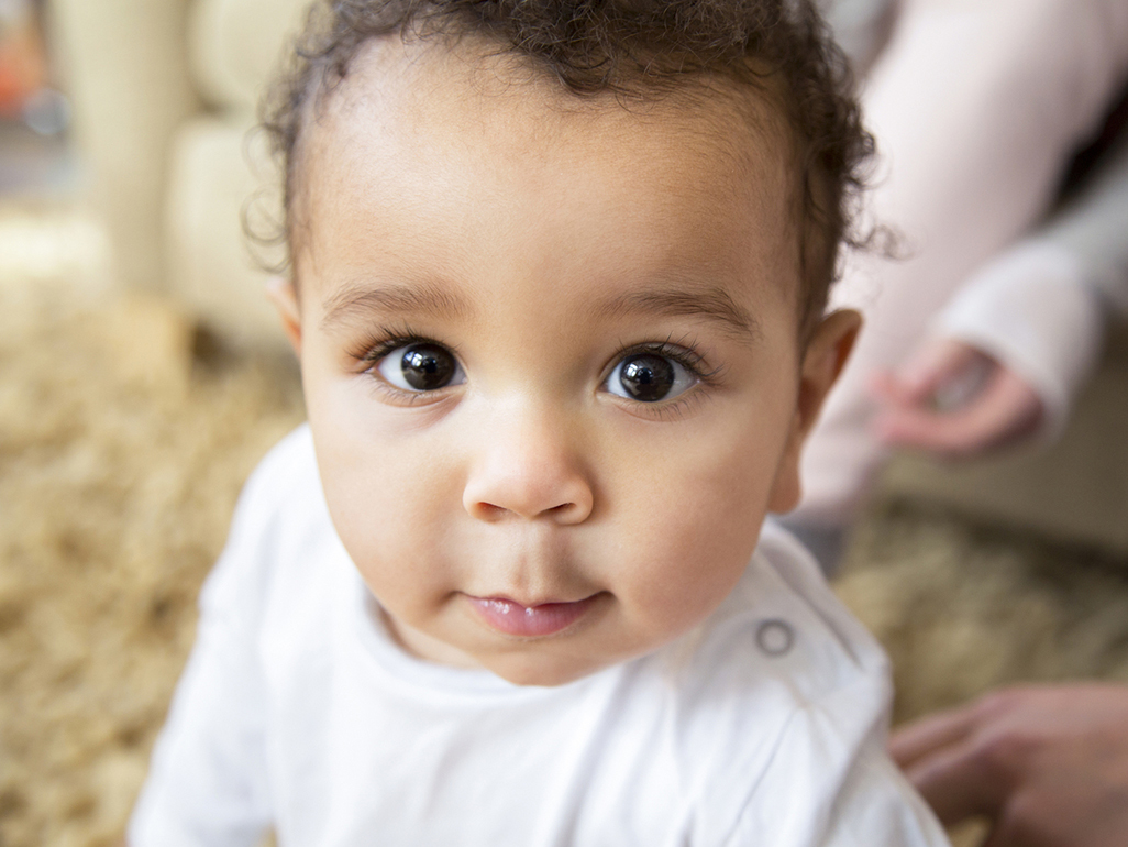 baby looking up at camera with adults in background