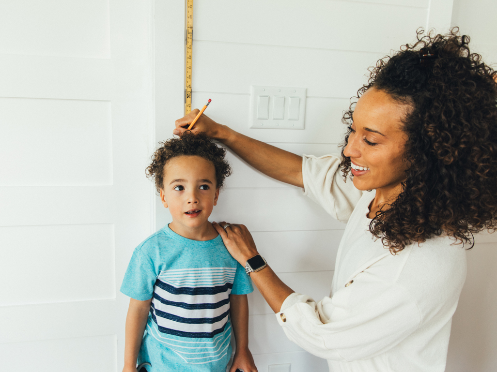 Mom measuring her son's height with a ruler